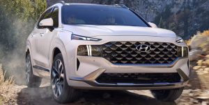 A white 2021 Hyundai Santa Fe being driven in a rocky forested area. | Hyundai dealer in Fort Smith, AR.