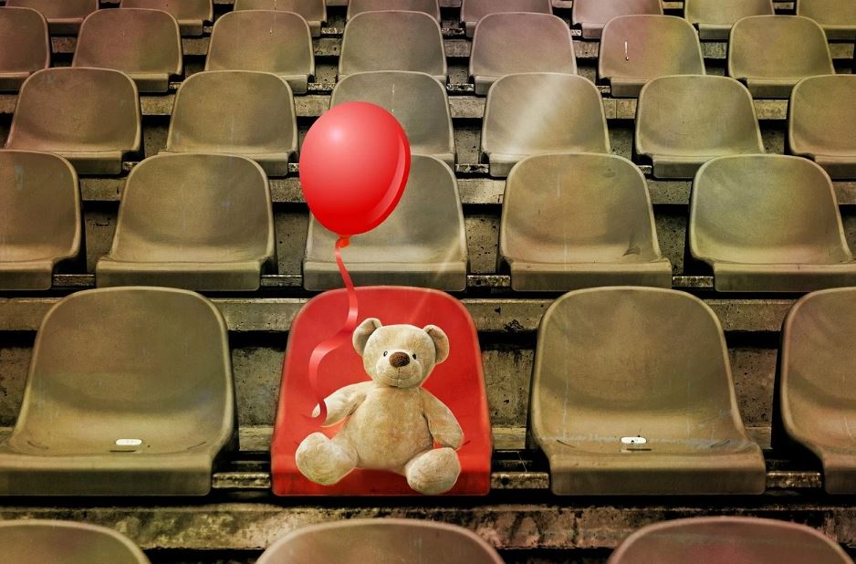 A stuffed bear holding a red balloon seated in a stadium surrounded by empty chairs. | Things to do in Fort Smith, AR | Crain Hyundai of Fort Smith