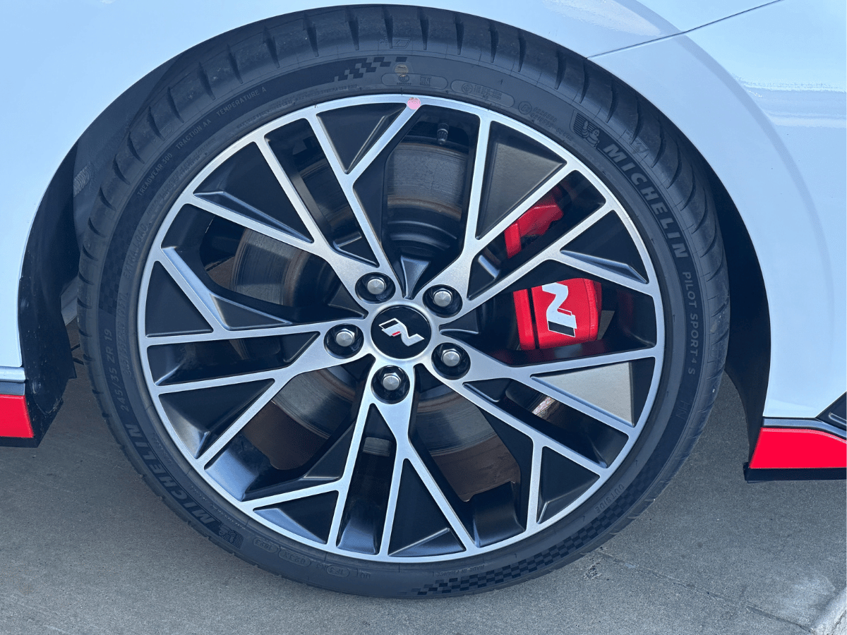 Close-up of a Hyundai N performance wheel and red brake caliper, showcasing the brand's bold design and precision engineering.