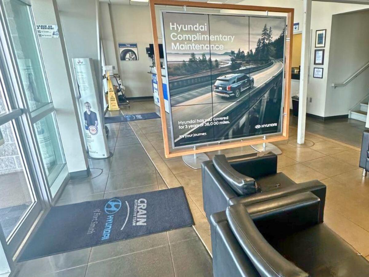 Inside the Crain Hyundai of Fort Smith service lounge featuring seating and a display promoting Hyundai Complimentary Maintenance for local drivers.