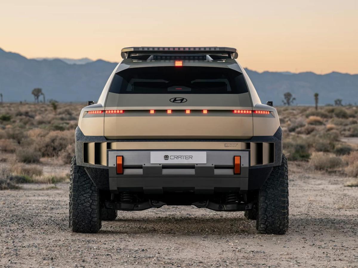 Rear view of the gold Hyundai CRATER Concept EV parked in a desert, showing pixelated taillights, 33-inch off-road tires, and a rugged rear skid plate.